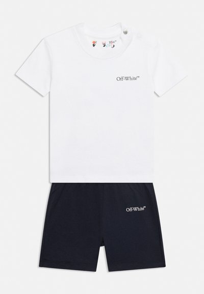 Бяла тениска с къси ръкави с логото "Off-White" и черни къси панталони с подходящо лого, предназначени за деца.