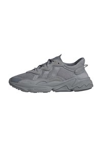 Scarpe atletiche grigie con tomaia in rete e sovrapposizioni sintetiche. Presentano dettagli testurizzati, colletto imbottito e un design della suola massiccia.