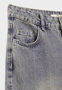 Nahaufnahme von verblichenen blauen Jeans, die Vorderstasche, kleine Münztasche, Gürtelschlaufe und Nähte des Bunds zeigen.