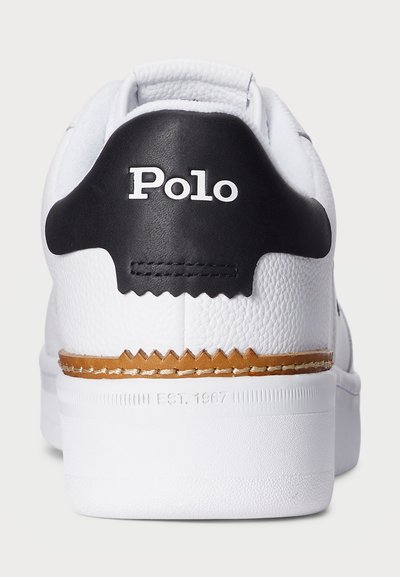 Hvit lær sneaker bak med svart hæltabu, "Polo"-logo, brunt lærkant og "EST. 1967" preget på sålen.
