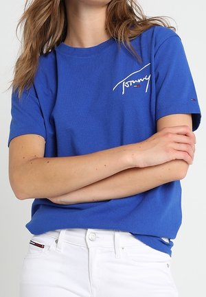Blauwe katoenen t-shirt met een ronde hals en korte mouwen. Voorzien van witte geborduurde "Tommy"-logo's en kleine logo-accenten op de mouw.