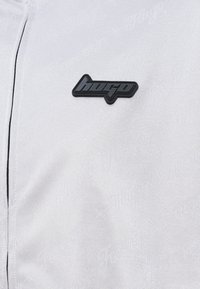 Balts auduma sporta žakets ar melnu "hugo" logo uzšuvumu uz krūts, ar smalku tekstūru un minimālistisku dizainu. Melni rāvējslēdzēja akcenti.