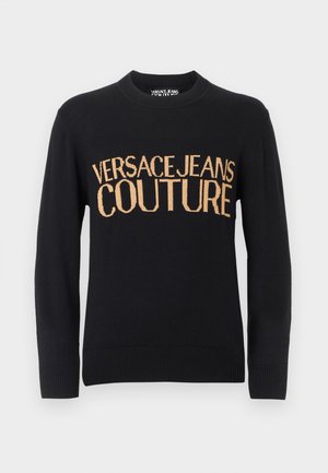 Svart genser med lange ermer og rund hals, med ribbekanter ved mansjetter og nederst, og stor beige tekst "VERSACE JEANS COUTURE" over brystet.