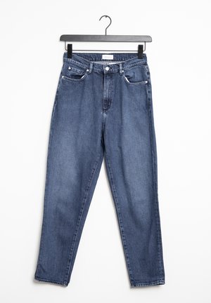 Blå højtaljede jeans med lige ben der hænger på en sort bøjle mod hvid baggrund, med forreste knapper og lommer.