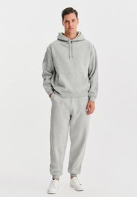 Szara bluza z polaru z kieszenią z przodu, w zestawieniu z szarymi spodniami dresowymi. Dopełnieniem stroju białe trampki. Miękka faktura, luźny krój.