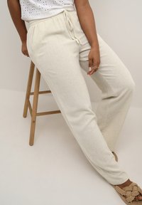 Pantaloni jogger bej, texturat, cu talie elastică și șnur. Asortați cu sandale tricotate în nuanțe neutre.