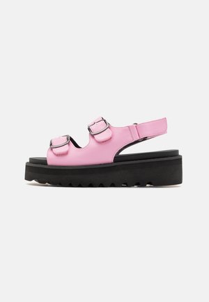 Sandale plateforme en cuir rose avec deux brides réglables à boucle et une semelle noire épaisse à bande adhérente striée.