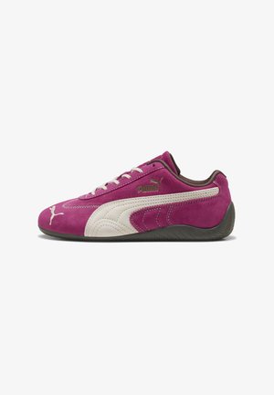 Puma sneakers i pink ruskind og hvide detaljer har et lavprofil design, flade snørebånd og en struktureret gummisål. Logoet er vist på siden.
