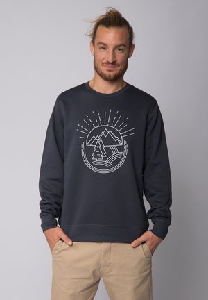 Marine sweatshirt met een witte berg en boom grafiek met zonnestralen. Geribbelde manchetten en zoom, relaxte pasvorm. Gemaakt in combinatie met beige broek.