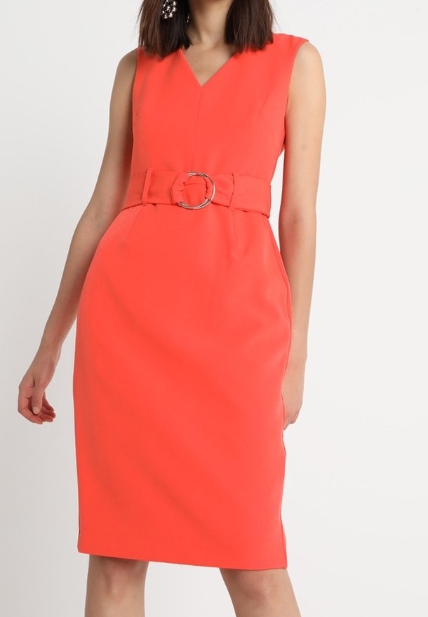 Ljusa korallfärgade ärmlösa klänning med V-ringning, figurnära form, bälte i midjan med rund metallspänne, och slät, strukturerad tyg.