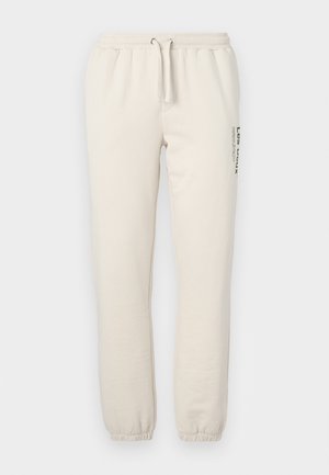 Pantaloni de trening bej, fabricați din bumbac moale, cu un talie elastică și șnur, manșete ribbate și un design imprimat pe lateral.