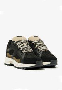 Black and beige athletic shoes with mesh panels, textured black suede, bold patterned laces, and a white rubber sole.