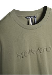 T-shirt en coton vert olive avec un col rond, portant un texte brodé "MORATO" sur le devant et un design à coupe décontractée.