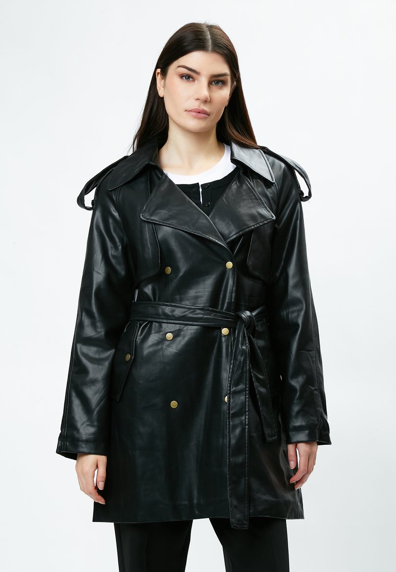 Abrigo de cuero negro con un diseño de doble botonadura, grandes solapas, botones dorados y un cinturón a juego atado a la cintura.