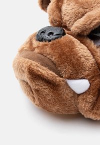 Juguete de perro de felpa marrón con forma redondeada, pelaje texturizado, nariz de plástico negro y dientes de fieltro blanco. Realzado con costuras detalladas.