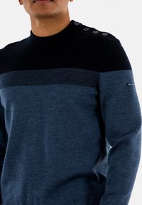 Maglione a righe blu e navy con scollatura rotonda, dettagli con bottoni sulla spalla e tessuto a maglia texturizzato.