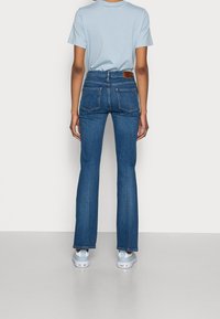 Korkeavyötäröiset siniset farkut slim fit -mallissa, valmistettu denimistä, jossa on klassinen muotoilu takataskuilla ja nahkapaikalla.