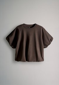 Løs, mørkebrun T-shirt med korte ærmer og opsamlede puffede ærmer, vist mod en ensfarvet lys grå baggrund.