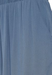 Jasnoniebieska, teksturowana tkanina z plisami i marszczoną talią, z bocznymi kieszeniami wkomponowanymi w projekt.