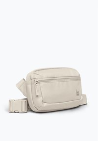 Borsa a tracolla beige realizzata in tessuto resistente, con un compartimento principale con zip, tasca frontale e tracolla regolabile con fibbia.