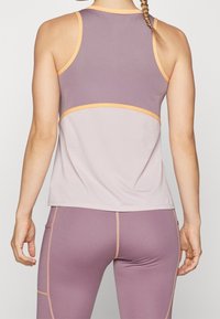 Top sportivo senza maniche in rete viola chiaro, con accenti arancioni e un design delle cuciture a contrasto. Tessuto testurizzato per la traspirabilità.