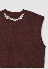 Burgunderfarbener ärmelloser Pullover mit strukturiertem Strick und dekorativer Blumen-Jewel-Verzierung am Ausschnitt.
