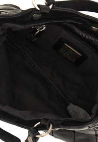 Interno di una borsa nera in pelle, caratterizzato da una texture liscia, tasca con cerniera e accessori metallici. Il compartimento principale è non foderato e scuro.