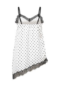 Robe nuisette blanche à pois noirs, bretelles noires réglables et bordure en dentelle noire le long du décolleté et de l'ourlet asymétrique.