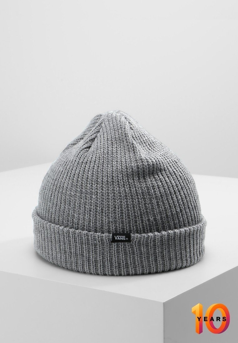 Bonnet côtelé gris avec bordure repliée et petite étiquette noire du logo Vans, présenté sur un socle blanc sur un fond uni.