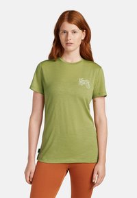 Grön t-shirt med korta ärmar i lätt material, med en liten vit cykelgrafik på bröstet. Platt nederkant och rund halsdesign.