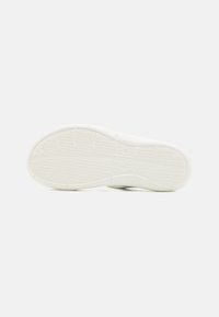 Hvid sneakersål med struktureret grebsmønster. Har afrundede kanter og en glat overflade. Ingen synlige mærker eller accenter.