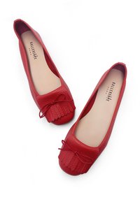 Bailarinas rojas de cuero con un acabado texturizado, que presentan un detalle de flecos en forma de ondas y un lazo en la punta. Forro interior suave.