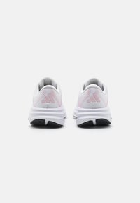 White athletic shoes with pink accents, mesh upper, cushioned sole, and three-stripe logo at the heel. Minimalist design and lightweight build.