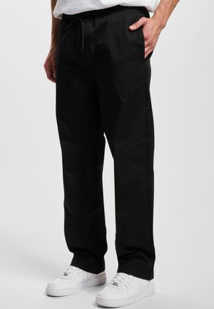 Svart bomullsblend joggebukser med elastisk linning, snøring, sidelommer og rett bendesign, kombinert med hvite sneakers.