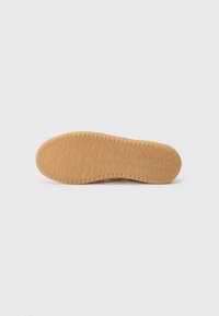 Suola in gomma con superficie texturizzata, colore beige chiaro, caratterizzata da distinti motivi a zigzag e logo del marchio impresso al centro.