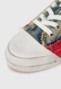 Τζιν αθλητικό παπούτσι με φθαρμένη υφή, κόκκιν α υφασμάτινα στοιχεία, λαμπερό ασημί κάλυμμα στα δάχτυλα και λευκά κορδόνια. Στρογγυλεμένο σχήμα στα δάχτυλα και λαστιχένια σόλα.