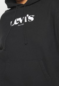 Felpa nera con logo bianco di Levi's e testo "Dal 1873" sul petto, dotata di tasca frontale a marsupio e cordini per il cappuccio.