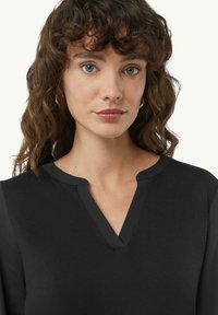 Schwarzes Oberteil mit V-Ausschnitt und weichem Material, lange Ärmel und minimalistisches Design. Sauberer und moderner Look.