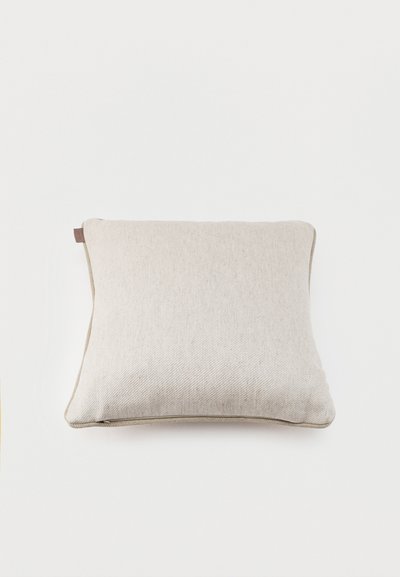 Coussin carré beige avec une housse en tissu texturé et des détails de coutures subtiles sur un fond blanc uni.