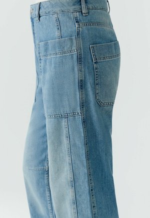 Lichtblauwe spijkerbroek met meerdere zakken aan de zijkant en achterkant, met zichtbare stiksels en een losse pasvorm.