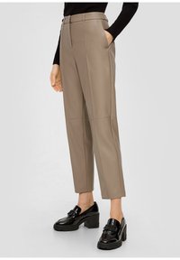 Beige faux leren broek met een hoge taille, rechte pijpen en twee zijzakken. Gepaarde met zwarte hakken loafers.