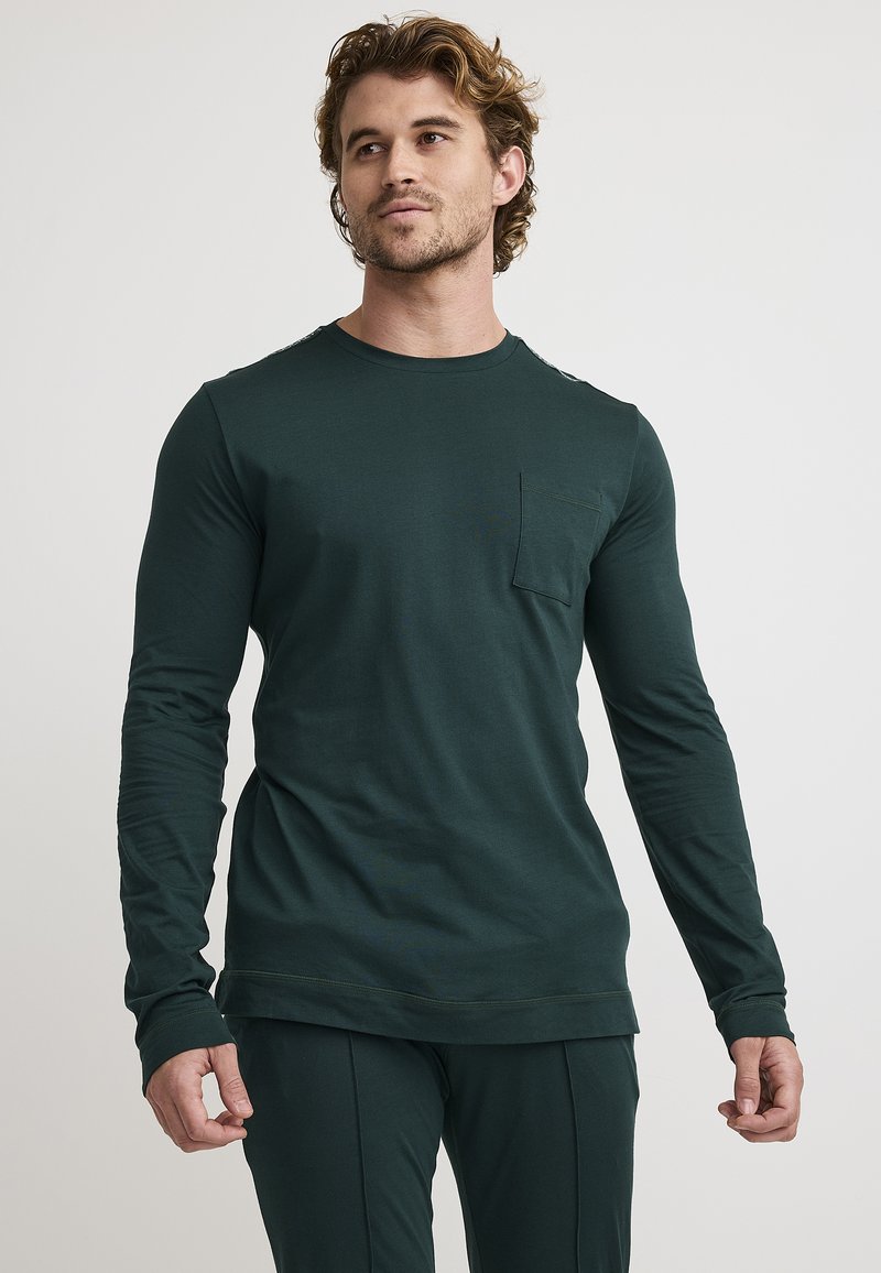 Camisa de manga larga de color verde oscuro, hecha de un tejido suave, con un escote redondo y un bolsillo en el pecho, con mangas ajustadas y un corte casual.