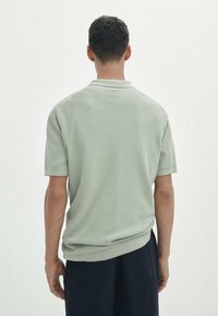 Kurzarm-Poloshirt aus leichtem, grünem Strickstoff, mit einem strukturierten Muster und einem einfarbigen Kragen, entworfen für eine lässige Passform.
