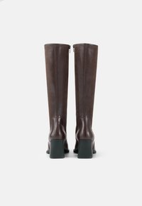 Brown leather knee-high boots with a smooth texture, back zippers, and a chunky green heel. The design is sleek and fitted.