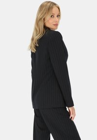 Czarna marynarka w prążki o dopasowanym kroju, z długimi rękawami i klapami typu notch, w komplecie z pasującymi spodniami. Gładka faktura.