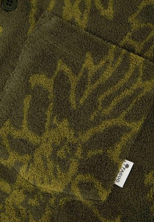 Dark green towel with yellow floral pattern, folded with a visible white fabric tag labeled "FAGUO" and a black button on corner.