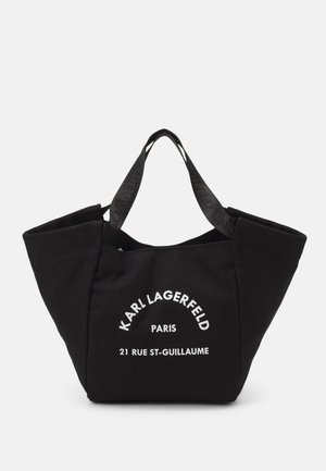 Czarna torba typu tote z szerokimi bokami, oznakowanymi rączkami i białym napisem "Karl Lagerfeld Paris 21 Rue St-Guillaume" z przodu.