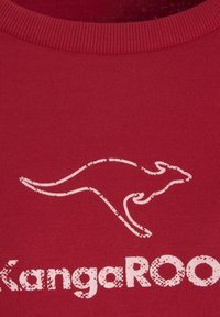 Rotes Baumwoll-T-Shirt mit einer weißen Silhouette eines Kängurus und abgenutzter Schrift "KangaROO" unter dem Motiv. Runder gerippter Ausschnitt.