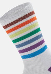 Bomullssockor med horisontella ränder i orange, grön, brun, blå och lila, allt på en vit bas. Ribbad textur upptill.