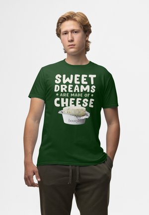 Maglietta verde con testo bianco in grassetto che recita "I DOLCI SOGNI SONO FATTI DI FORMAGGIO" accompagnato da un'illustrazione di formaggio in una tazza.